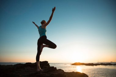 Güzel bir gün batımında okyanus kıyısında yoga yapan kadın.. 