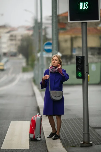 スーツケースを着た女性がバス停に立っている — ストック写真