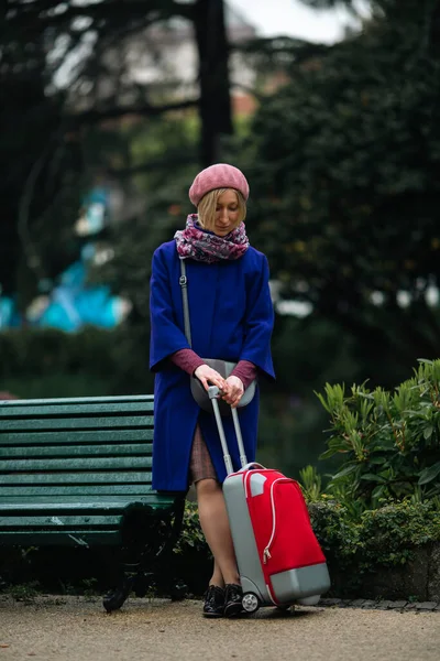 Μια Γυναίκα Κόκκινη Βαλίτσα Στέκεται Κοντά Ένα Παγκάκι — Φωτογραφία Αρχείου