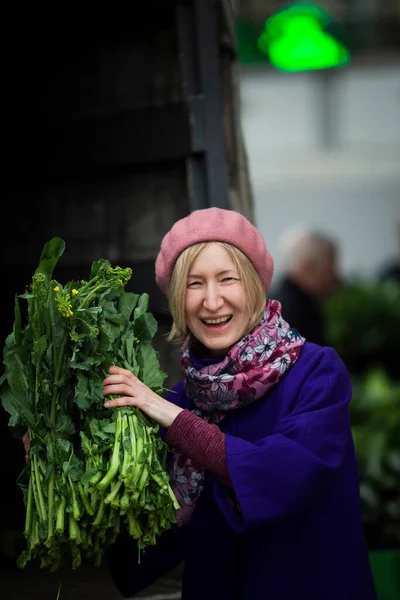一个快乐的女人从街上的商店里买东西 并炫耀一些美味的蔬菜 — 图库照片