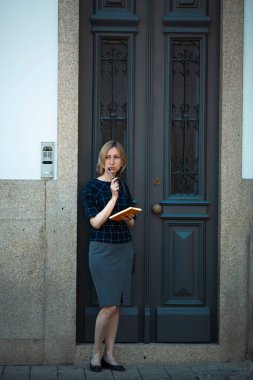 Porto, Portekiz 'deki geleneksel bir evin önünde elinde kalem ve defter olan bir kadın duruyor..