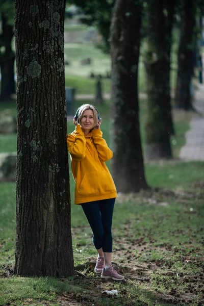 一个戴耳机的女人在公园里听音乐 — 图库照片