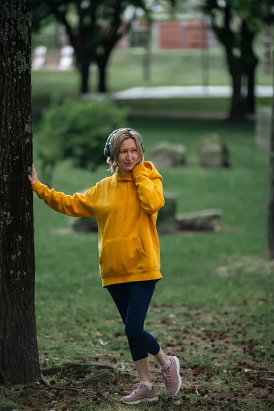 ヘッドフォンを装着した女性が公園で音楽を楽しむ — ストック写真