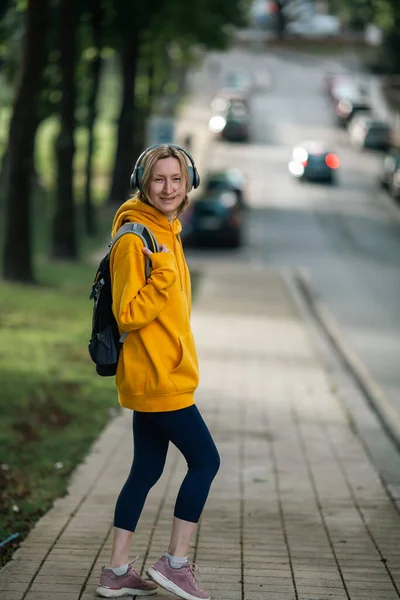 Kvinna Med Urban Ryggsäck Och Hörlurar Står Vid Vägen — Stockfoto