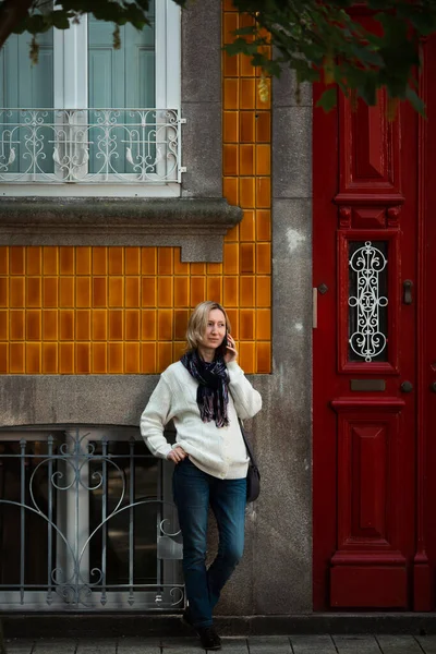 ポルトガルのポルトの伝統的な家の外に立っている間 女性は彼女の携帯電話で話します — ストック写真