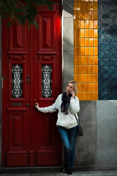 ポルトガルのポルトにある伝統的な家のドアの外の電話で話している女性 — ストック写真