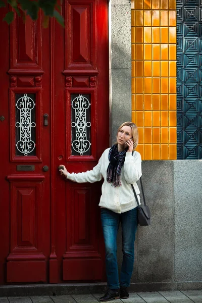 Μια Γυναίκα Μιλάει Στο Τηλέφωνο Στην Πόρτα Ενός Παραδοσιακού Σπιτιού — Φωτογραφία Αρχείου