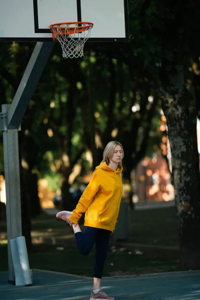 Een Vrouw Opwarmen Voor Een Jog Een Outdoor Basketbalveld — Stockfoto