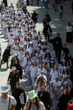 PORTO, PORTUGAL - 9 Mayıs 2023: Porto 'nun Queima das Fitas Geçidi - Portekizli üniversite öğrencilerinin yıllık şenliği. Mezunlar bir silindir şapka ve baston takıyorlar. İkisi de fakültenin renginde..