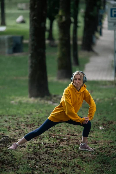 在城市公园里 一个女人在跑步前戴着耳机 — 图库照片