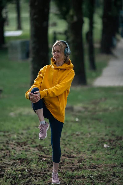 在城市公园里 戴耳机的女人在户外运动 — 图库照片