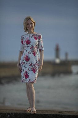 Deniz kenarında poz vermiş bir kadının uzun bir portresi..