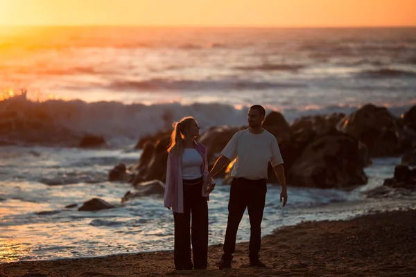 一对年轻夫妇在金色的日落时相遇在海滩上 — 图库照片
