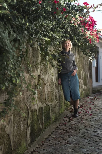 女性が旧市街の通りを歩くと 壁は緑と花で覆われています — ストック写真