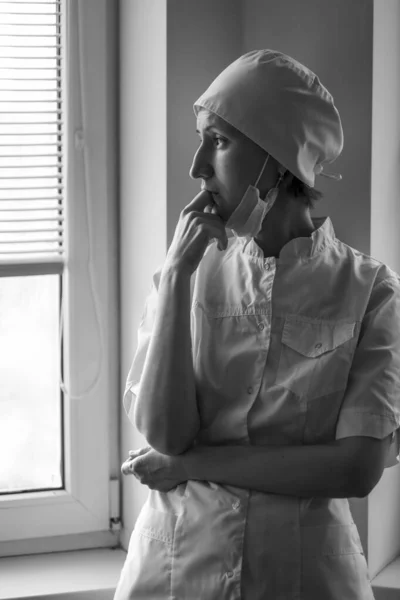 女性医師が窓の外を見ている 白黒写真 — ストック写真
