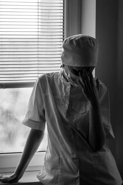 一位处于紧张状态的女医生站在窗前 黑白照片 — 图库照片