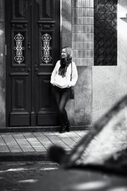 Tipik bir Portekiz apartmanının kapısında duran bir kadın. Siyah beyaz fotoğraf.