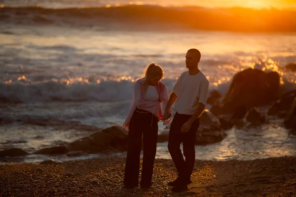 一对年轻夫妇在金色的夕阳西下的海滩上玩得很开心 — 图库照片
