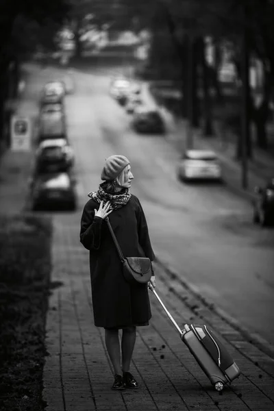 一个提着手提箱的女人站在路边 黑白照片 — 图库照片