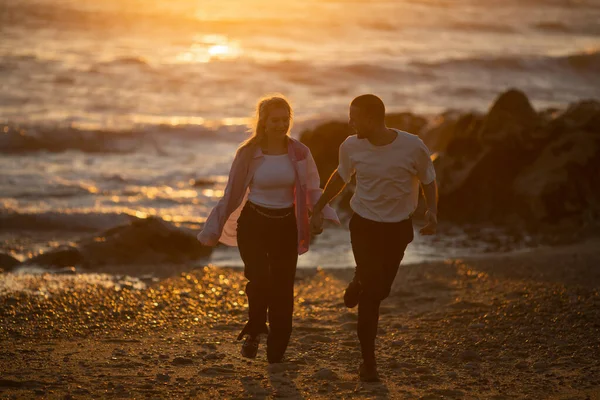 一对年轻夫妇在海滩上享受着金色的落日 — 图库照片