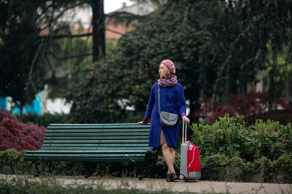 Una Mujer Está Parada Cerca Banco Parque Lleva Una Maleta Fotos de stock