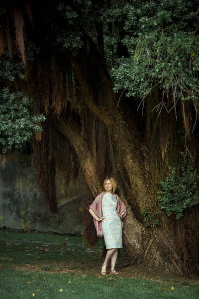 公園内の大きな木のそばに立つ女性像 — ストック写真