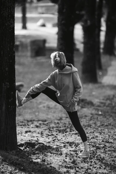 ヘッドフォンを装着した女性が野外で運動をしている 白黒写真 — ストック写真