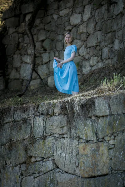 一个身穿蓝色衣服的女人站在一座中世纪城堡的废墟中 — 图库照片