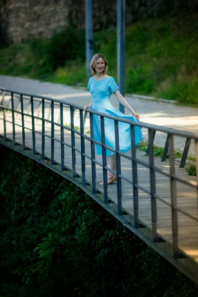 一个穿着蓝色衣服的女人站在河边的人行道上 — 图库照片