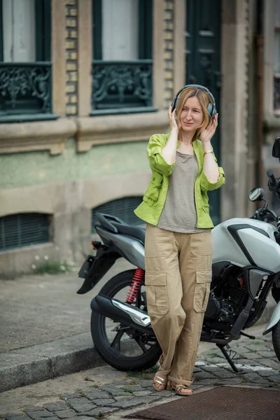 Woman Listens Music Headphones While Standing Motorcycle Street — Stock Photo, Image