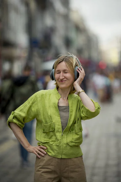 Una Mujer Está Escuchando Música Sus Auriculares Una Calle Llena —  Fotos de Stock