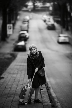 Sokakta bavullu bir kadın. Siyah beyaz fotoğraf.