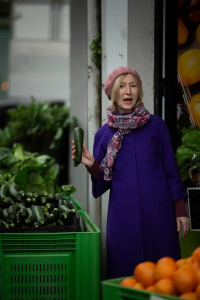 A woman with a cucumber in her hand in a vegetable store.