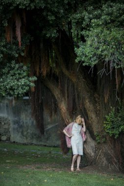 Bir kadın parktaki büyük bir ağaçtan randevu bekliyor.. 