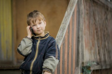 Küçük bir taşra çocuğu akıllı telefonuyla bir telefon görüşmesi yapıyor..