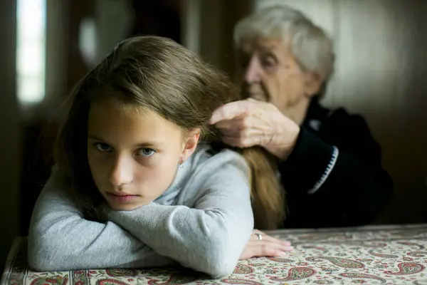 一位祖母给她灰心的孙女的头发编辫子 图库图片