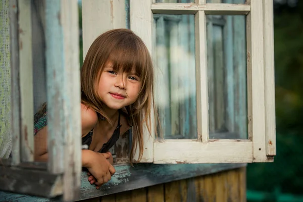 Portret Słodkiej Dziewczynki Wyglądającej Przez Okno Domu Wsi Zdjęcia Stockowe bez tantiem