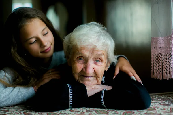 Küçük Bir Kız Yaşlı Büyükannesine Sarılıyor Yaşlı Kadın Kameraya Bakıyor Stok Fotoğraf