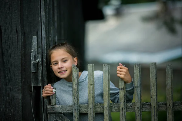 一个少女躲在农舍的木栅栏后面 免版税图库图片