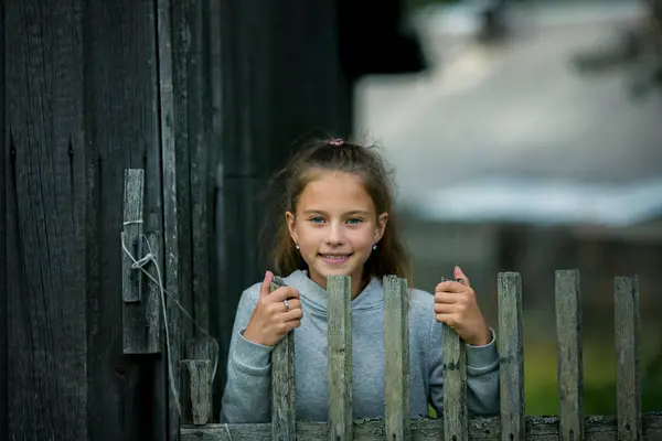 村子篱笆边的一个小女孩 免版税图库照片