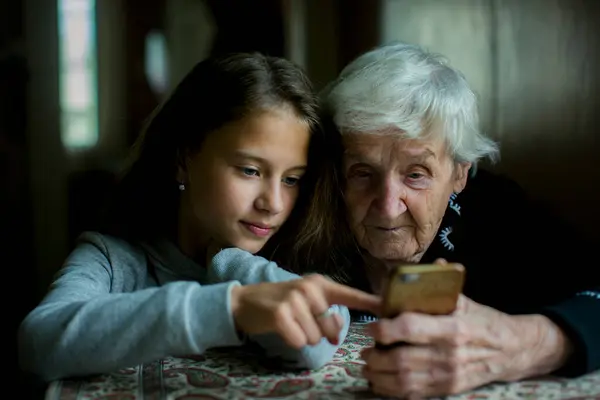 Een Meisje Leert Haar Oma Hoe Haar Smartphone Moet Gebruiken Stockafbeelding