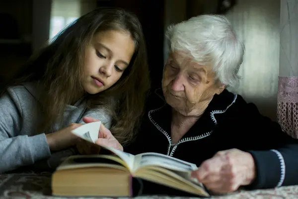 Una Anciana Está Leyendo Libro Con Nieta Imágenes de stock libres de derechos