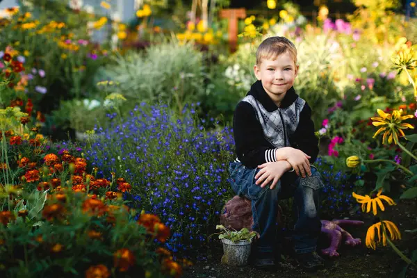 Ein Junge Sitzt Einem Garten Mit Blumen lizenzfreie Stockfotos