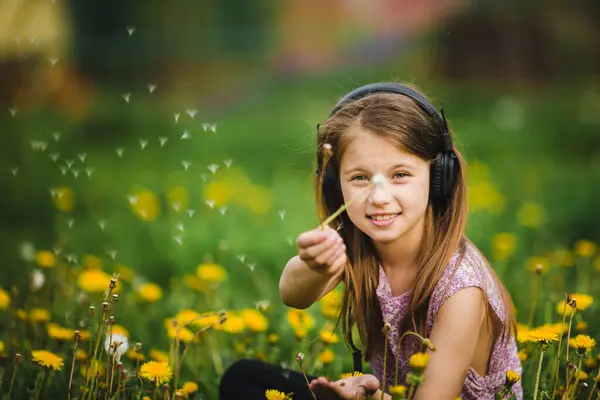 귀여운 소녀는 헤드폰을 민들레 플러프를 로열티 프리 스톡 이미지