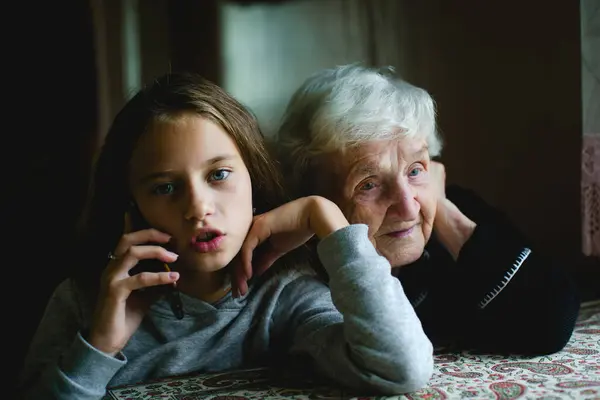 おばあちゃんは孫娘が電話で話しているのを耳にします ロイヤリティフリーのストック写真