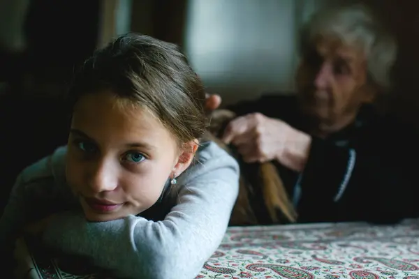 おばあちゃんは小さな女の子の髪を編む ロイヤリティフリーのストック画像