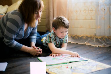 Bir kadın ve küçük oğlunun kitap okumaya daldığı bir sahne, bir kitap üzerinde özel bir bağ kurma anını paylaşıyorlar..