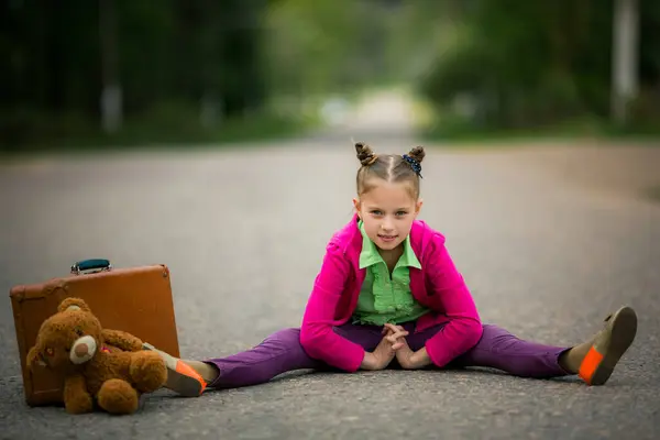 활기찬 소녀는 가방과 부드러운 장난감 모험에 준비가 도로에 스톡 사진