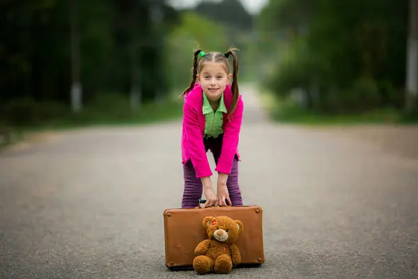 子供時代の探検 彼女のカラフルな衣装 スーツケース そしてかわいいおもちゃで 少女は彼女の周りの世界を探検し 新しい経験を熱望します ストック画像