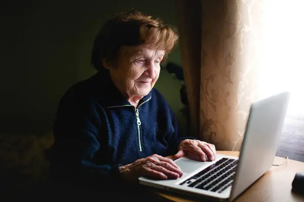 一位老年妇女正在一台笔记本电脑上工作 免版税图库图片